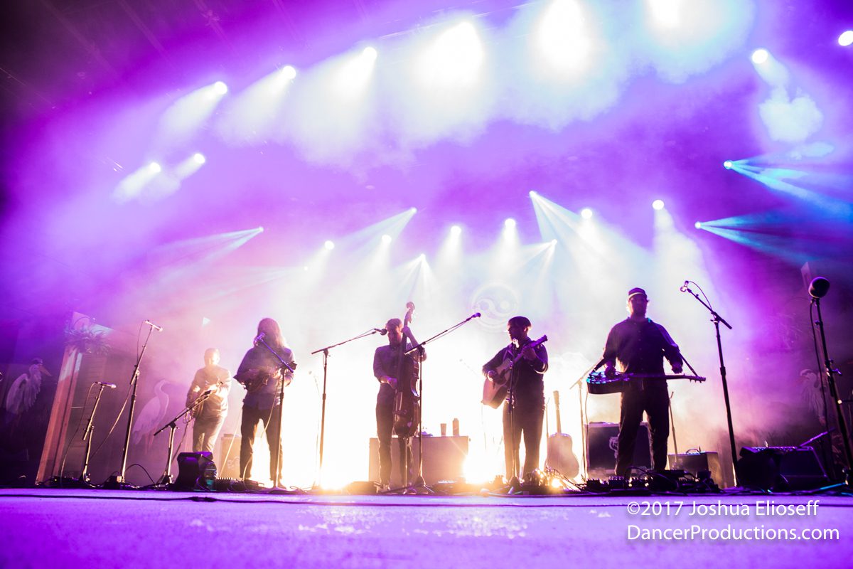 Band performing on stage with colorful lights.