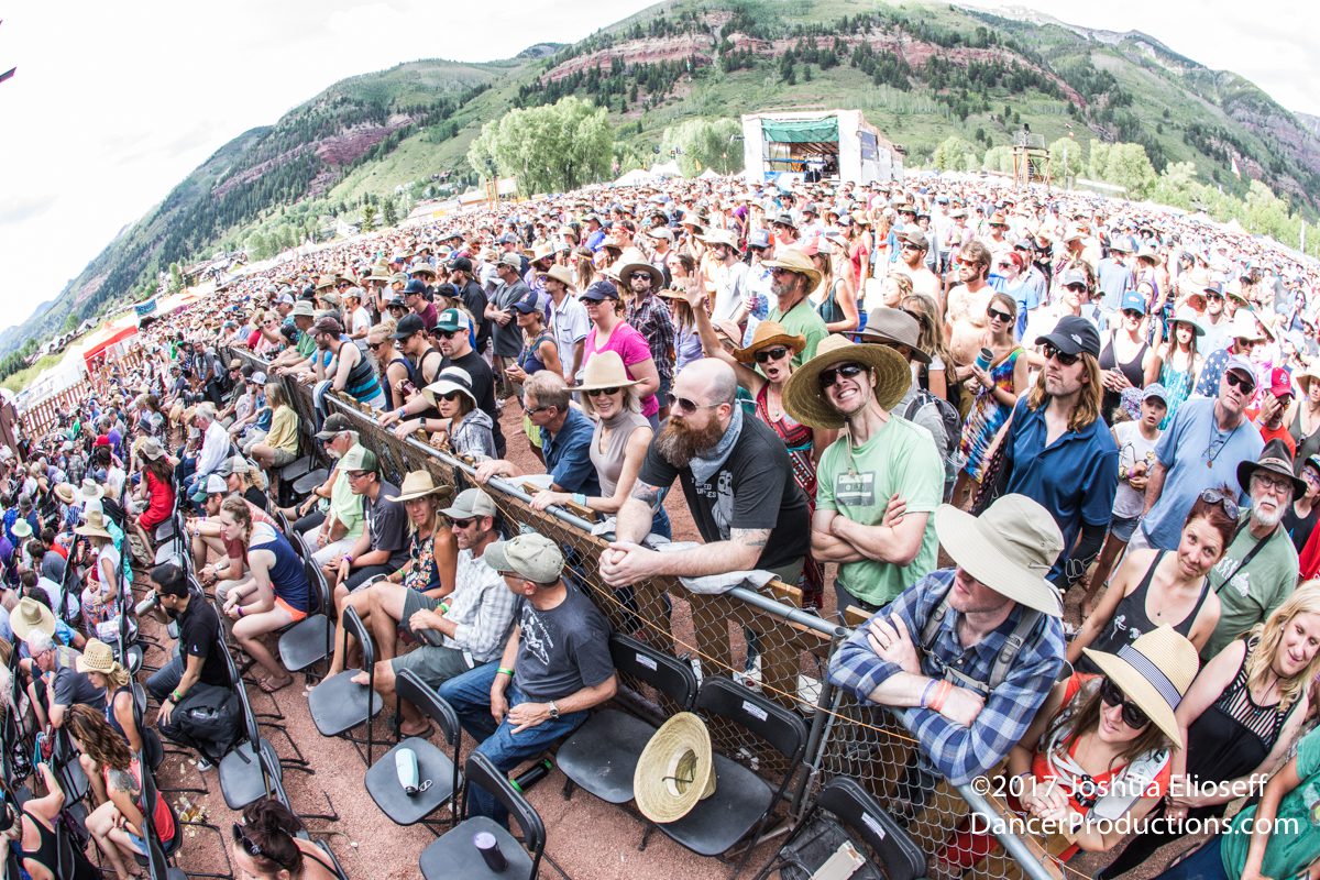 Outdoor music festival crowd with mountain backdrop.