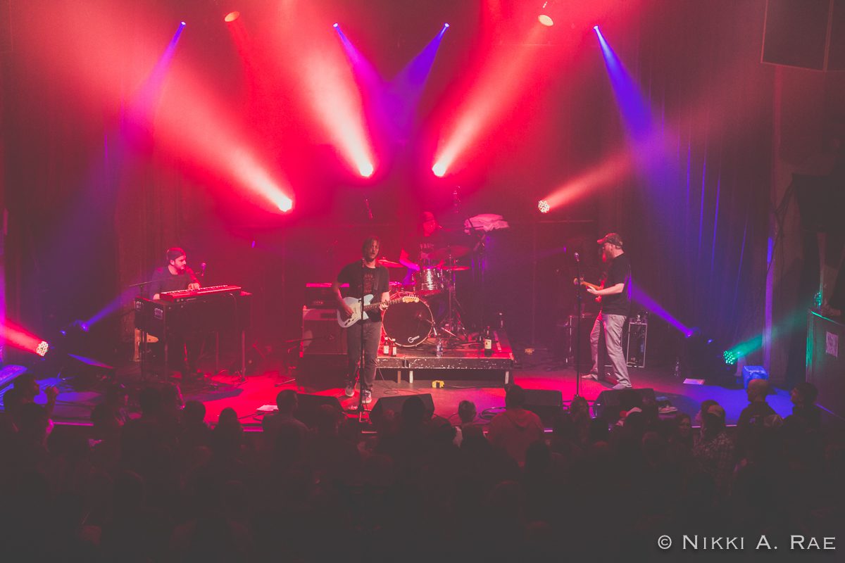 Band performing on stage with colorful lights.