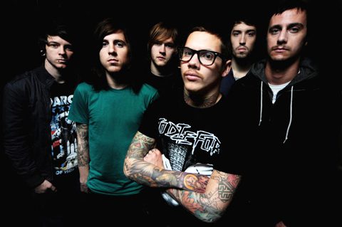 Six men standing in a dark setting.