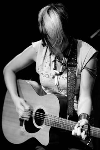 Musician playing acoustic guitar, black and white.