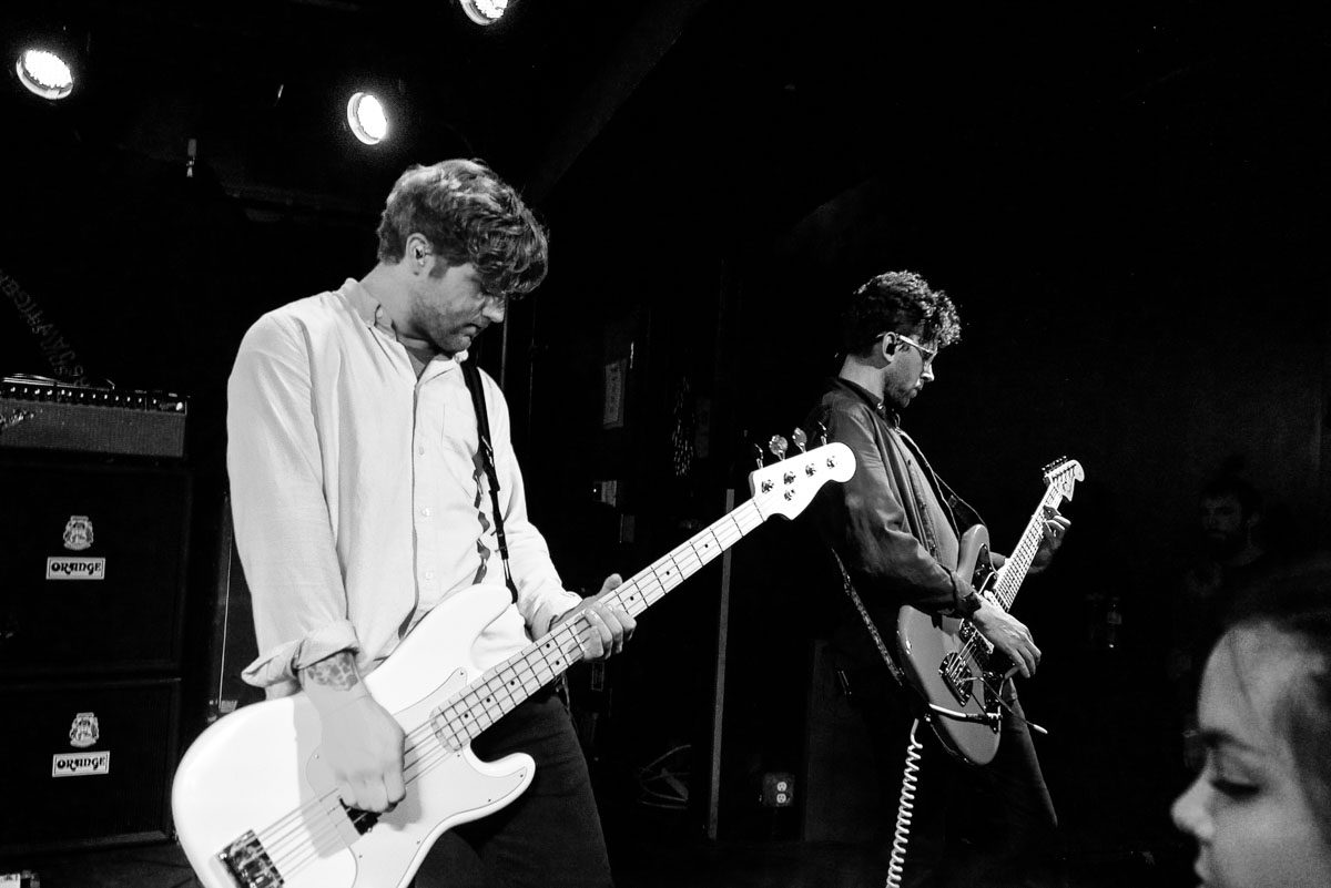 Two musicians performing on stage with guitars.