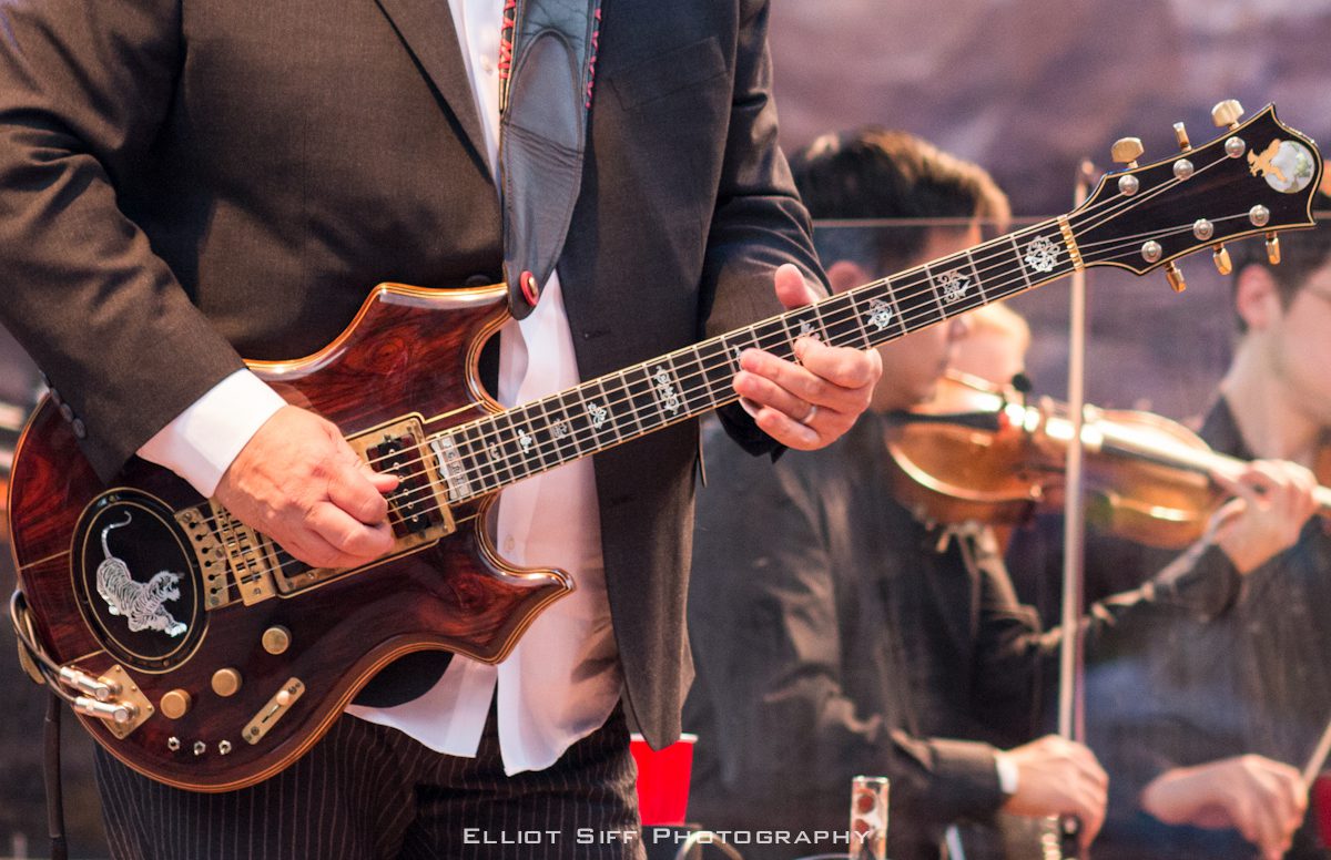 Musician playing electric guitar on stage.