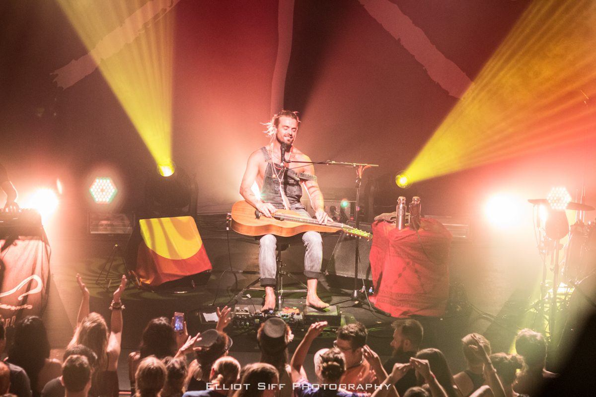 Musician performing on stage with guitar.