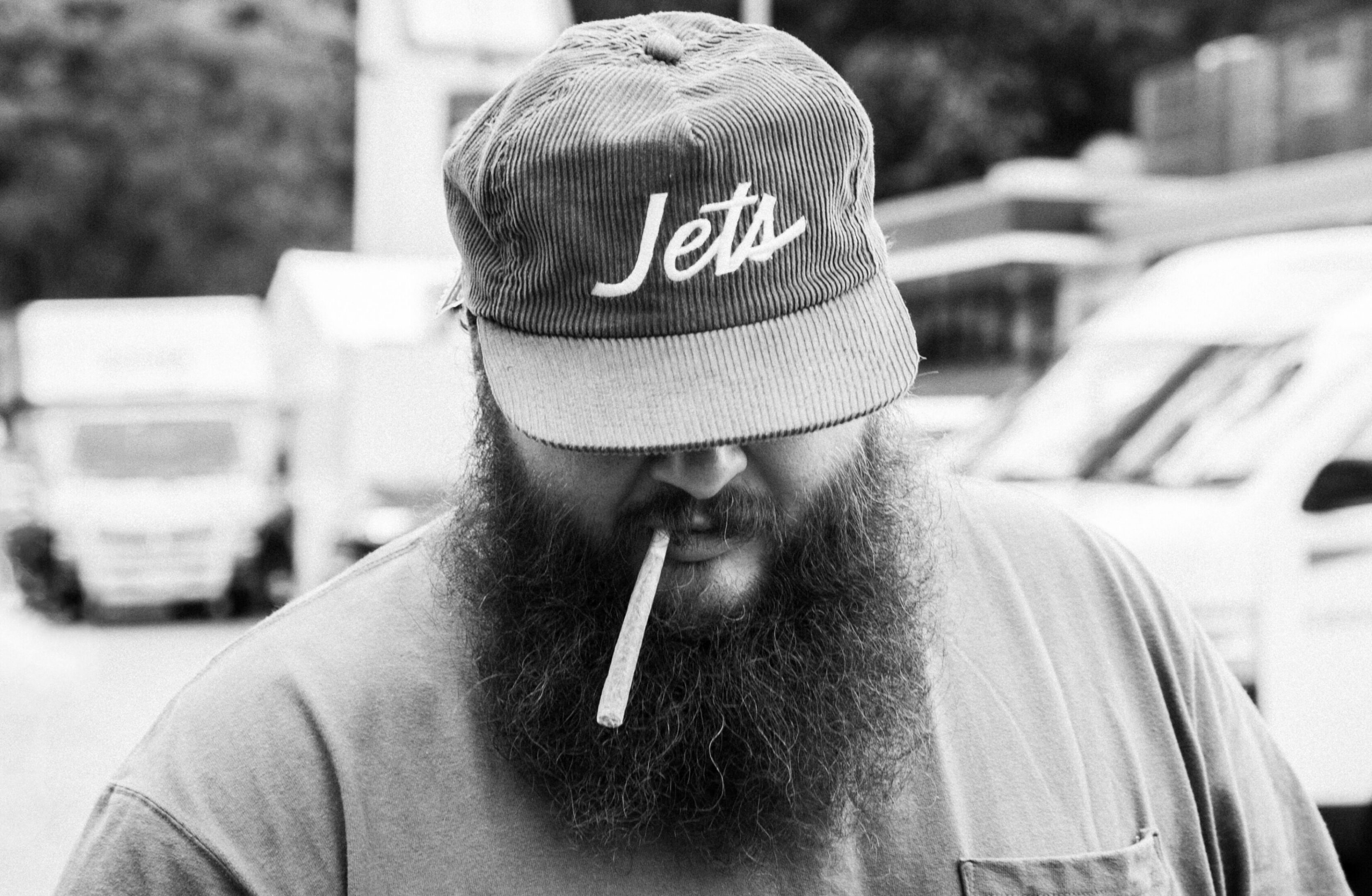 Man with beard, cap, smoking cigarette.