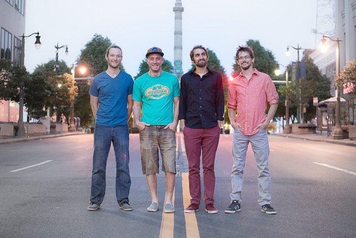 Four men standing on a city street.