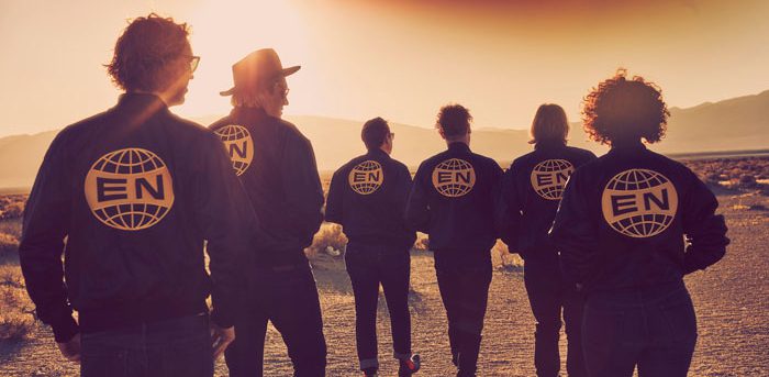 Group walking in desert wearing matching jackets.