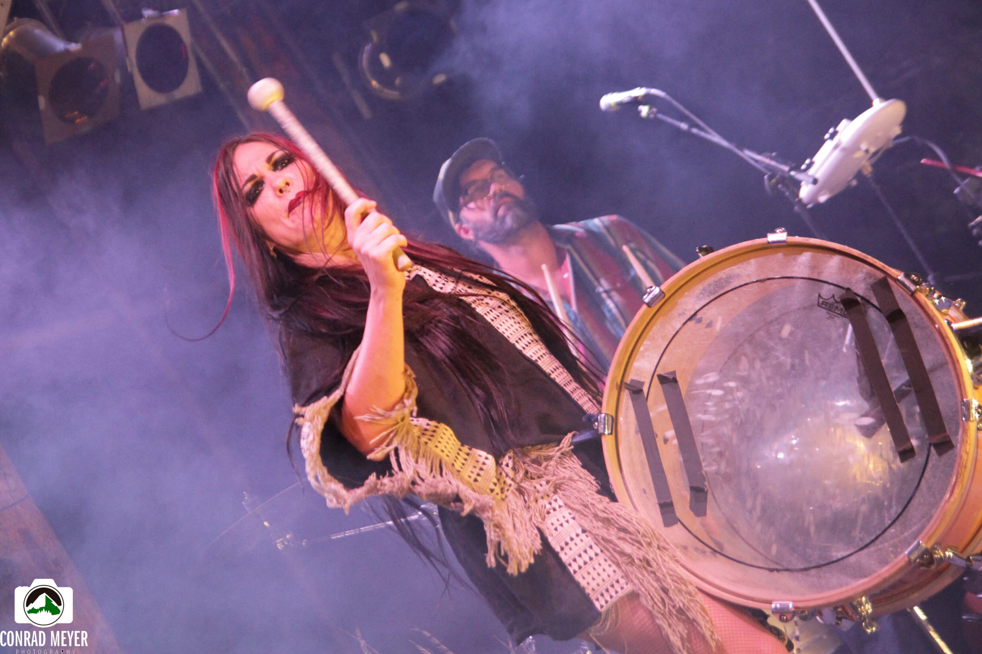 Woman playing drum on stage, lively performance.