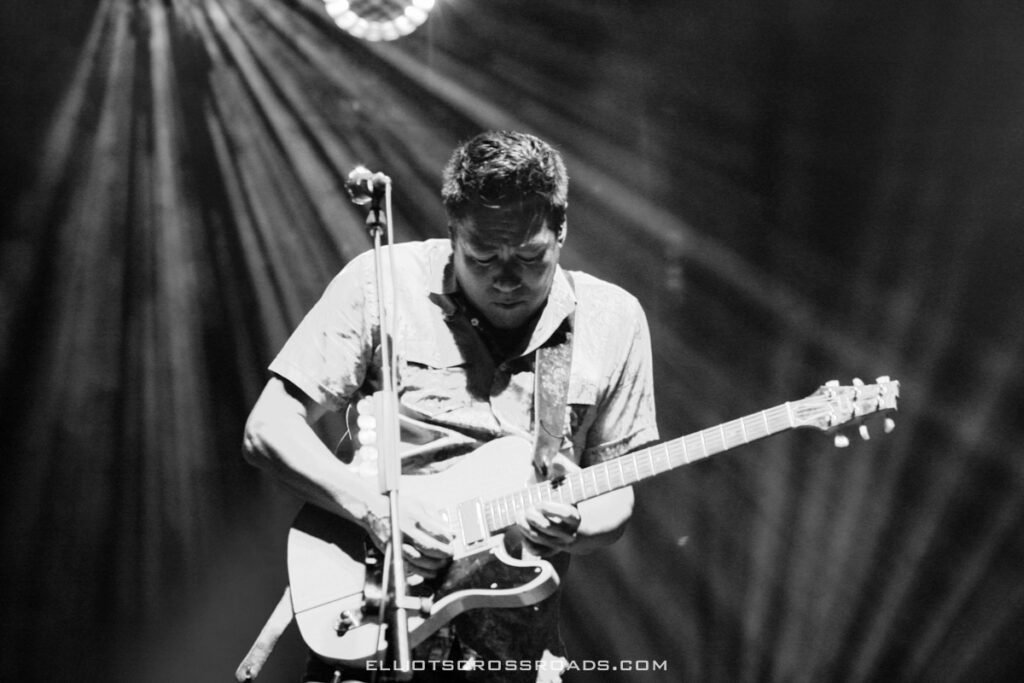 Musician playing electric guitar on stage.