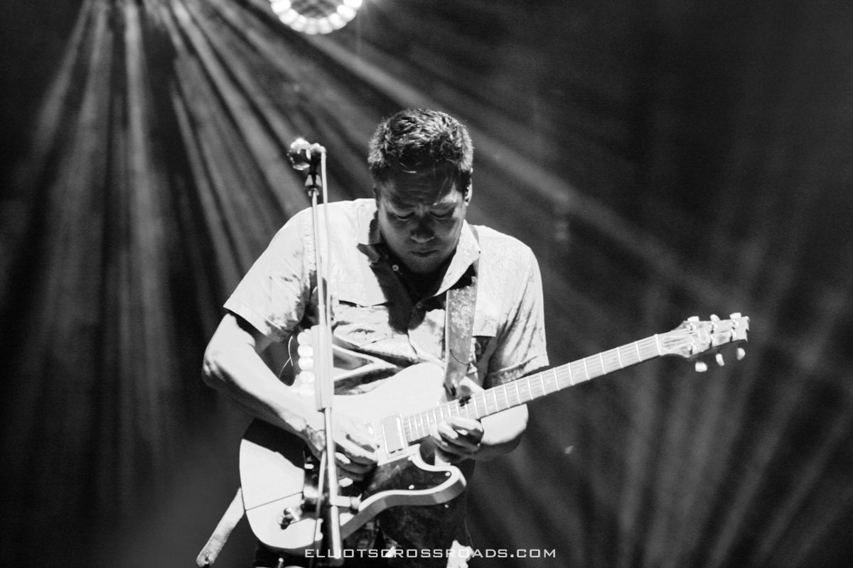 Musician playing electric guitar on stage.