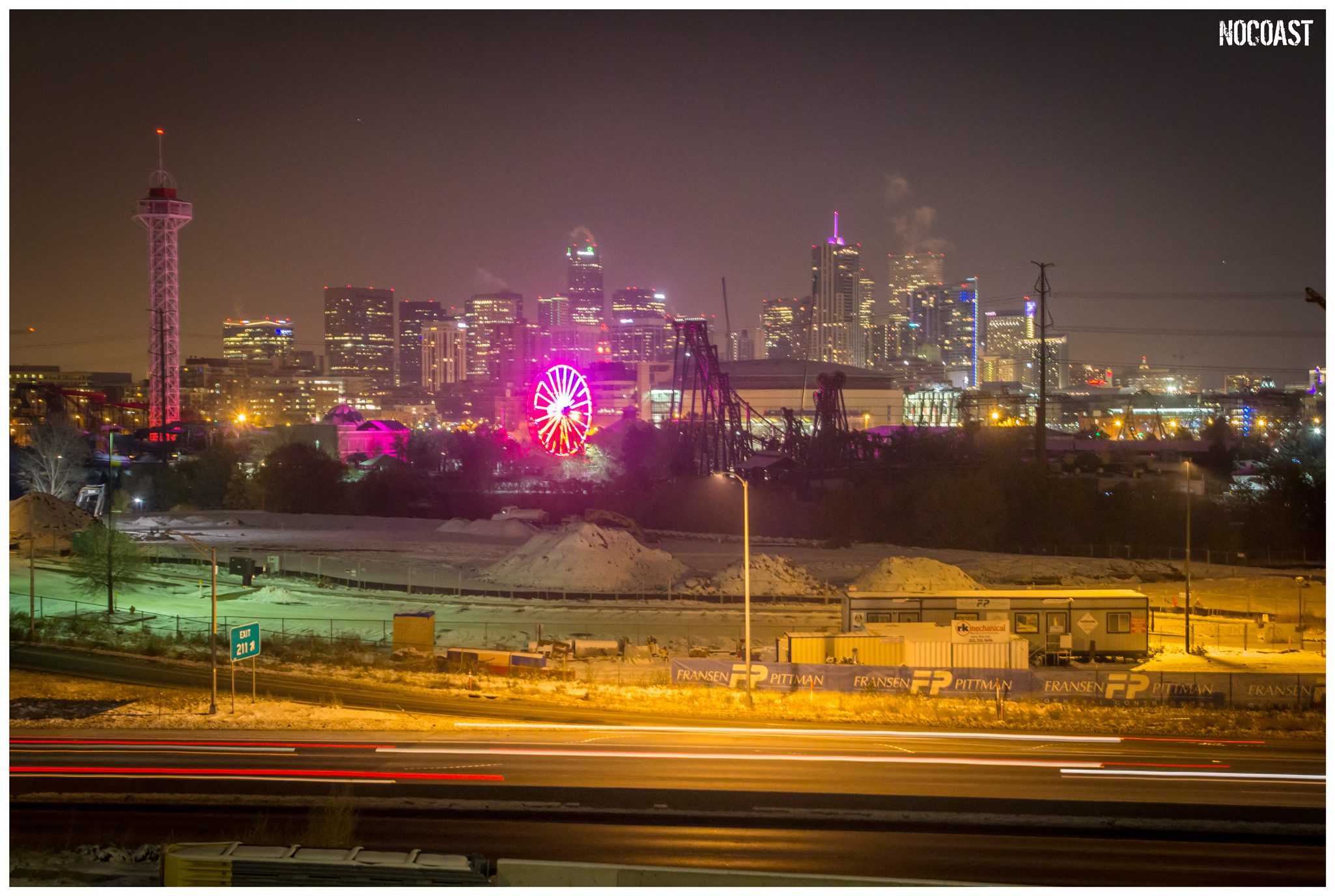 City skyline at night with illuminated Ferris wheel.