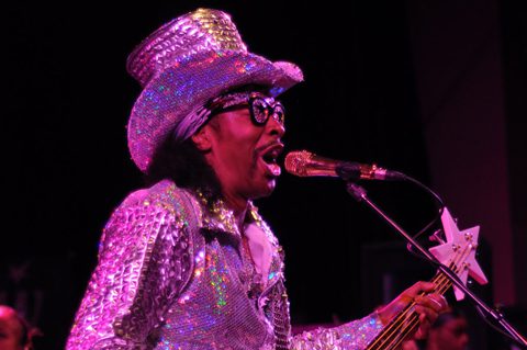 Musician performing in sparkly outfit on stage.