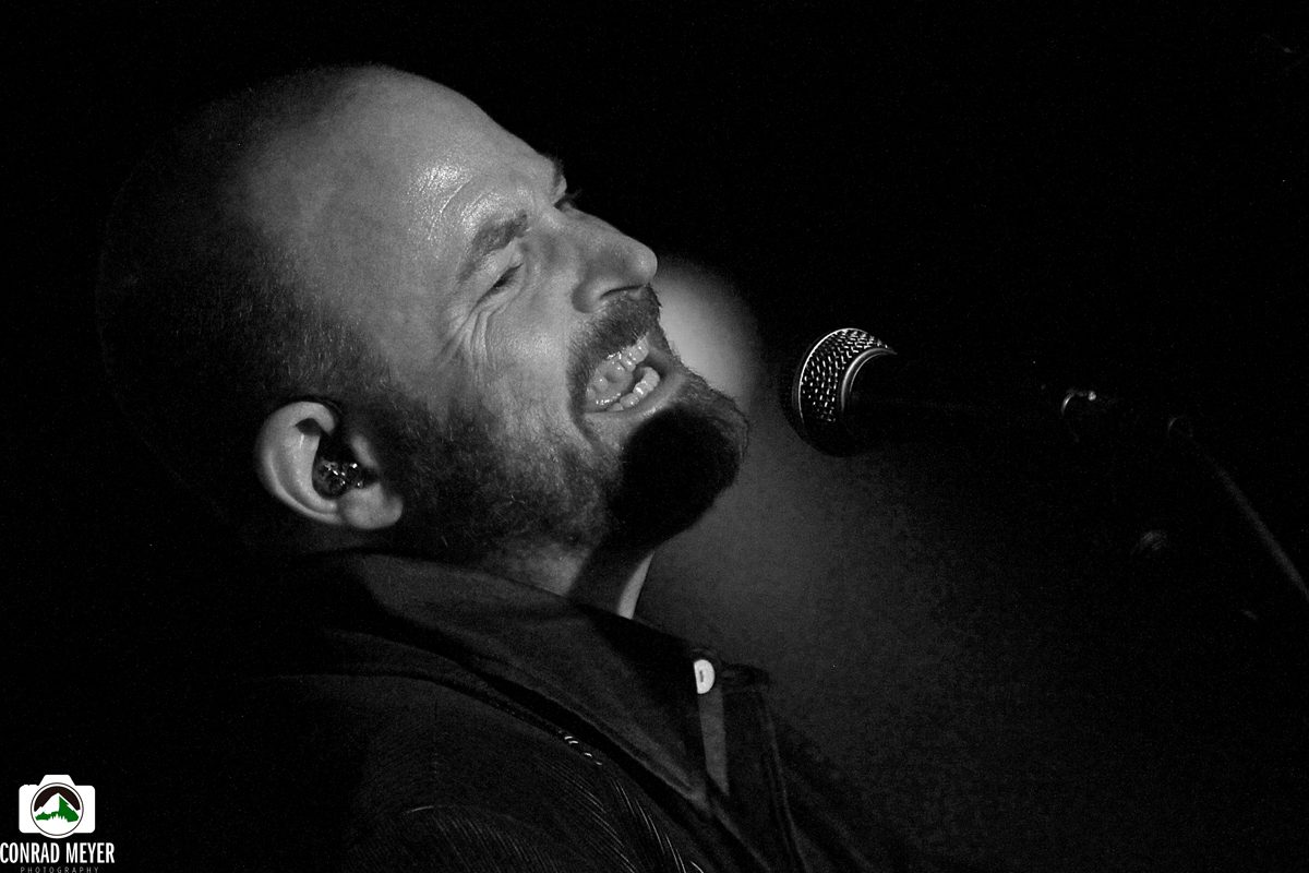 Singer passionately performing on stage, black-and-white.