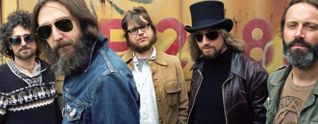 Five men standing in casual clothing outdoors.