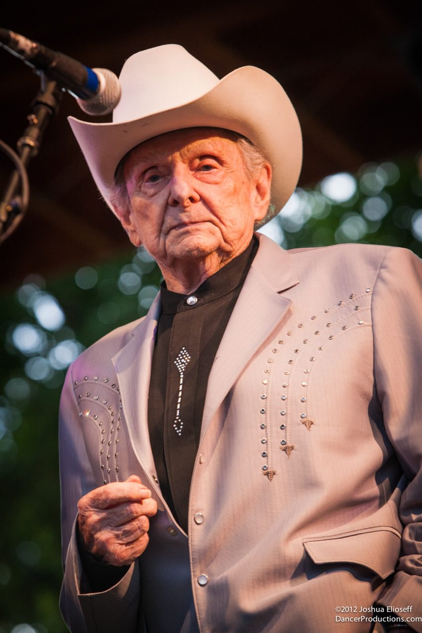 Elderly man in cowboy hat on stage.