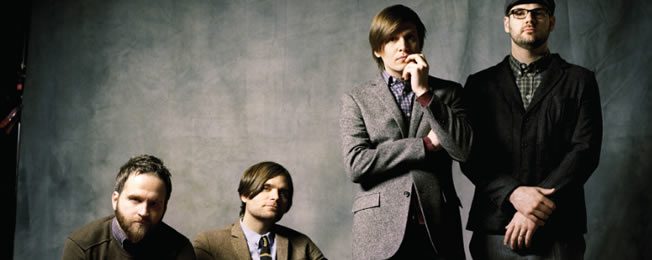 Four men in formal attire, posing together.