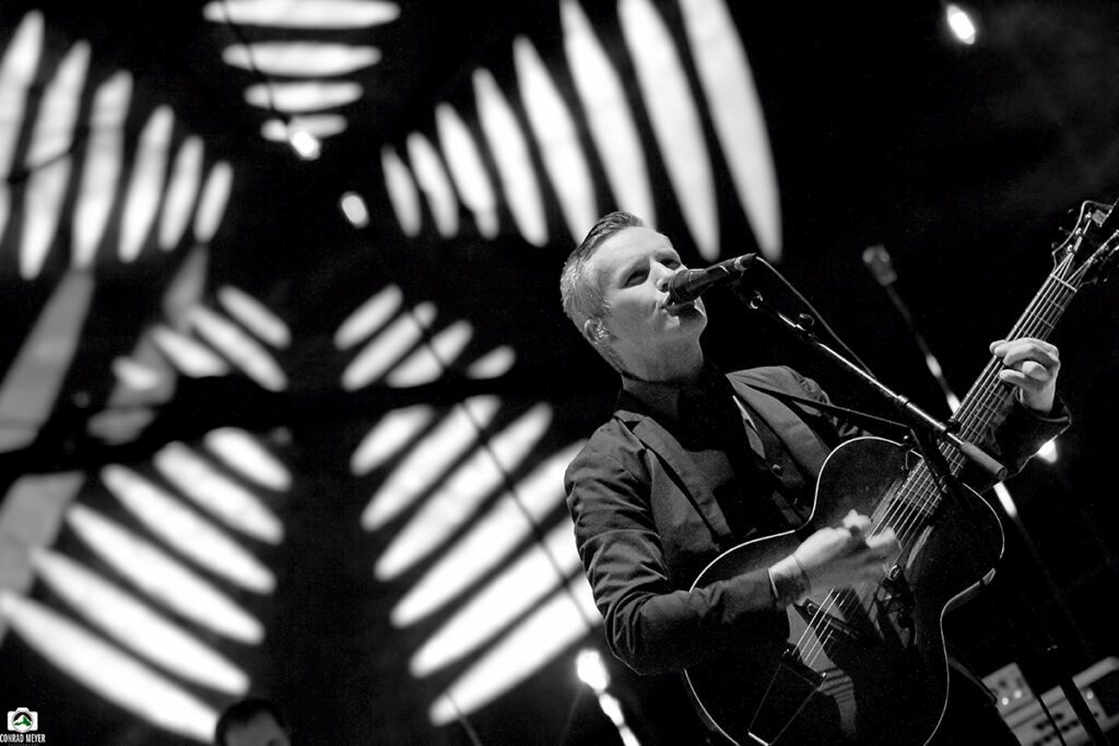 Singer performing on stage with guitar.