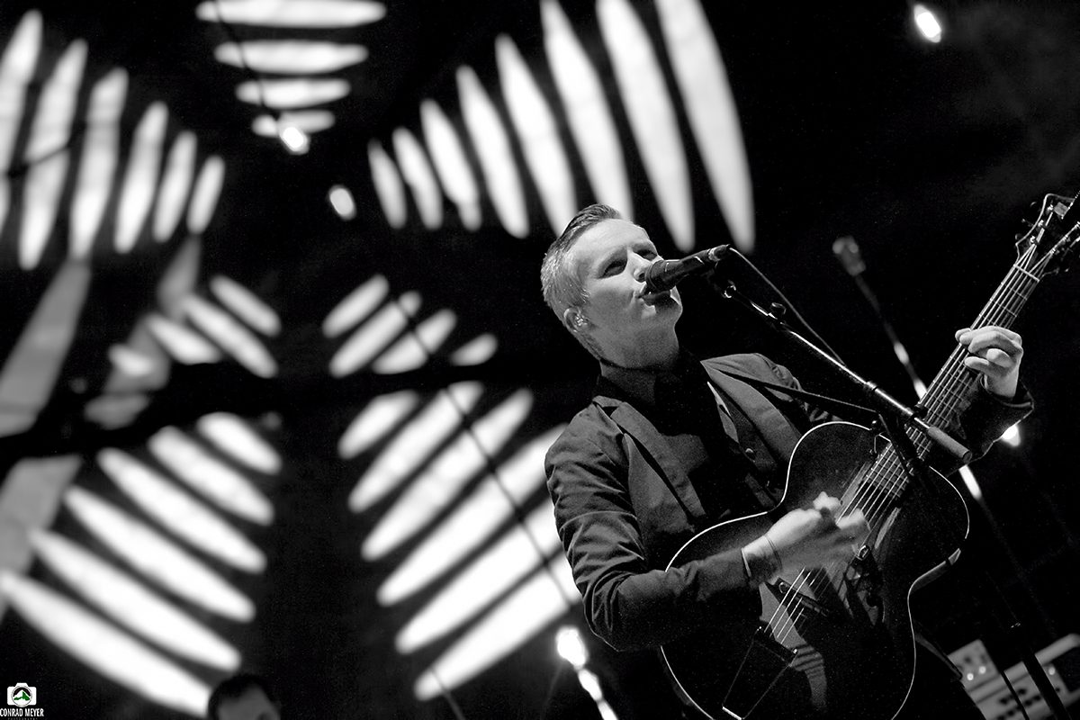 Singer performing on stage with guitar.