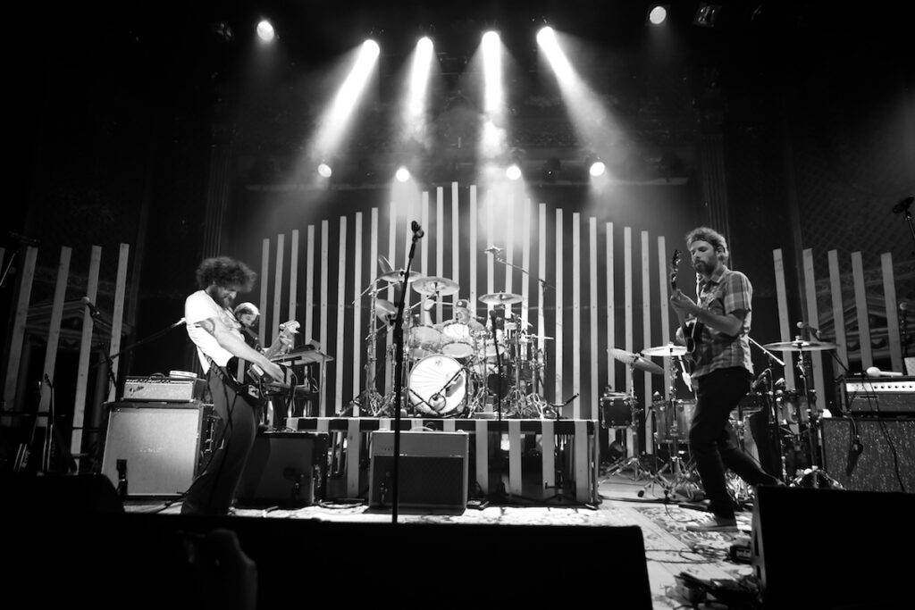Band performing energetically on stage, black-and-white.