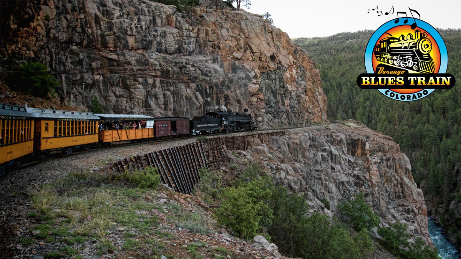 Train on mountain track with scenic backdrop.
