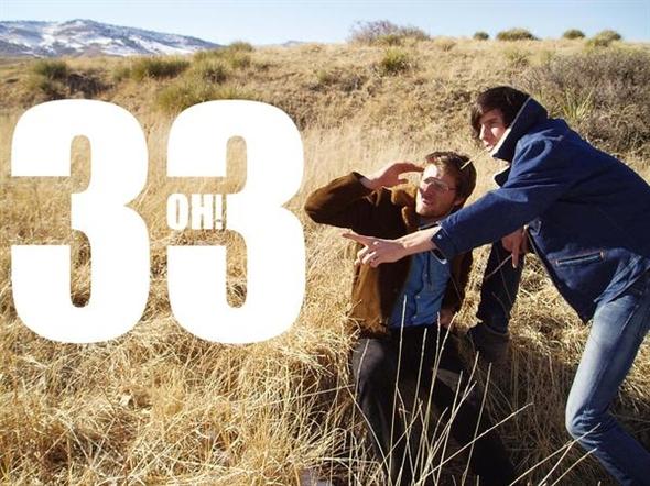 Two people in a grassy field, pointing.