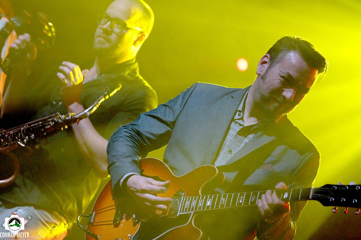 Musicians performing on stage with guitars.