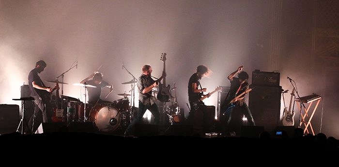 Band performing on stage with dramatic lighting.