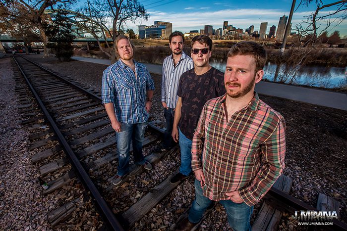 Four men standing on railroad tracks outdoors.