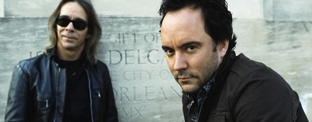 Two men posing in front of stone background.