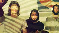 Three men with a guitar and projection.