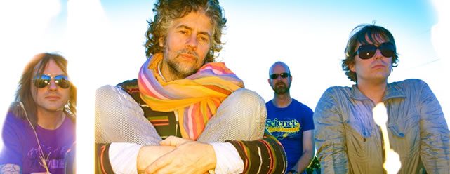 Four men sitting outdoors with colorful scarves.