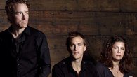 Three people posing against a wooden backdrop.
