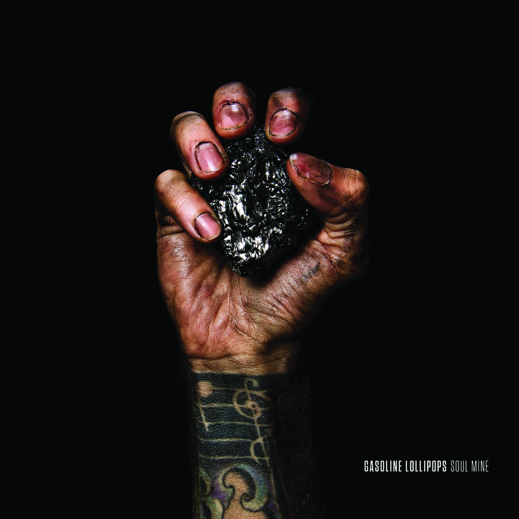 Tattooed hand gripping a piece of coal.