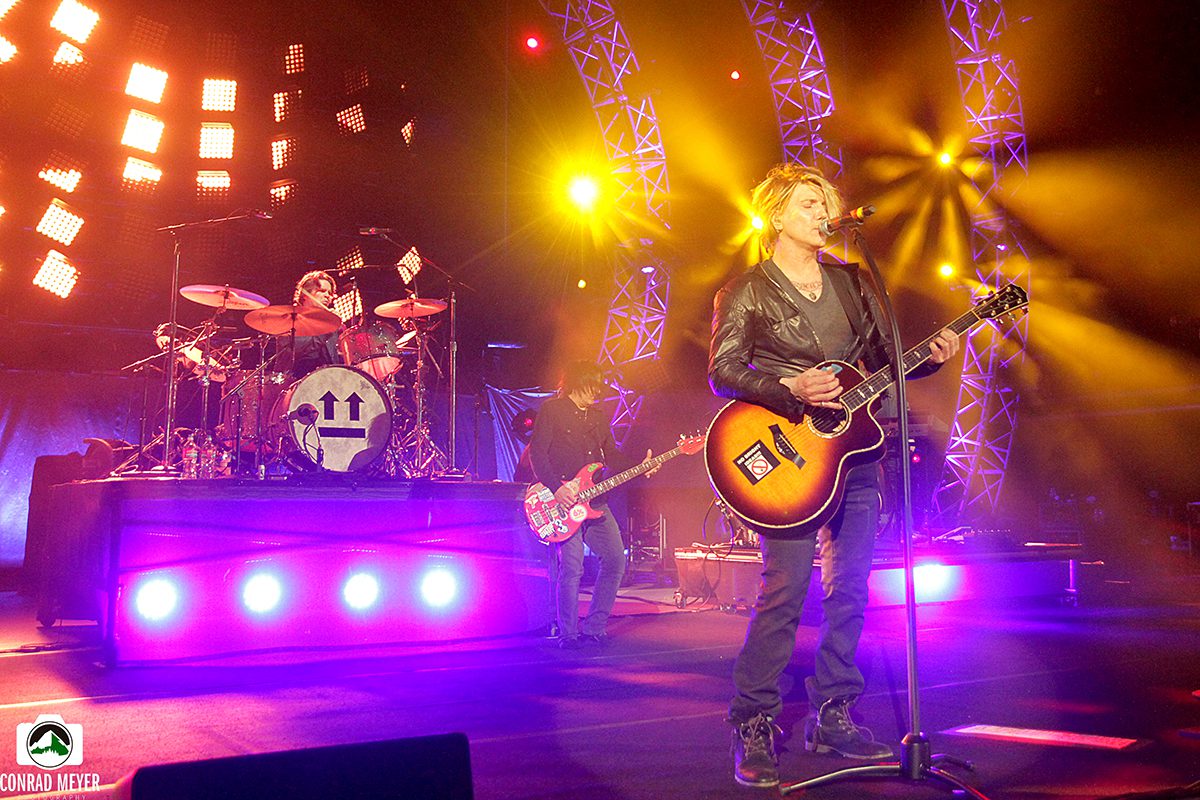 Band performing on stage with colorful lights.