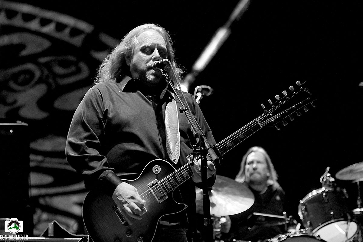 Musician playing guitar on stage, black and white.