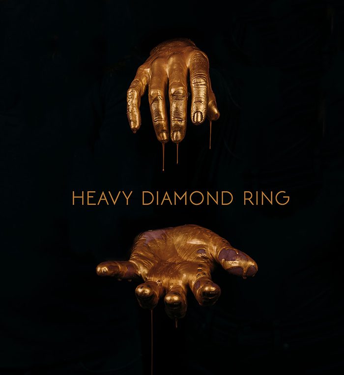 Gold hands sculpture with "Heavy Diamond Ring.