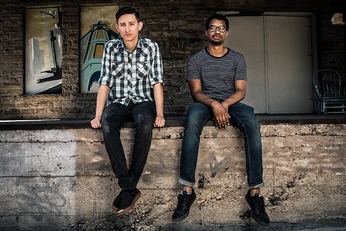 Two men sitting on a concrete ledge.