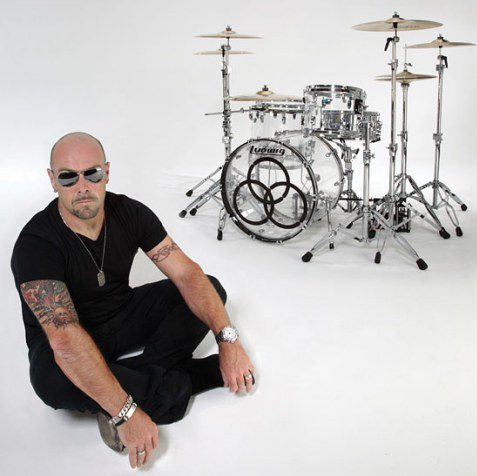 Man sitting near a drum set.