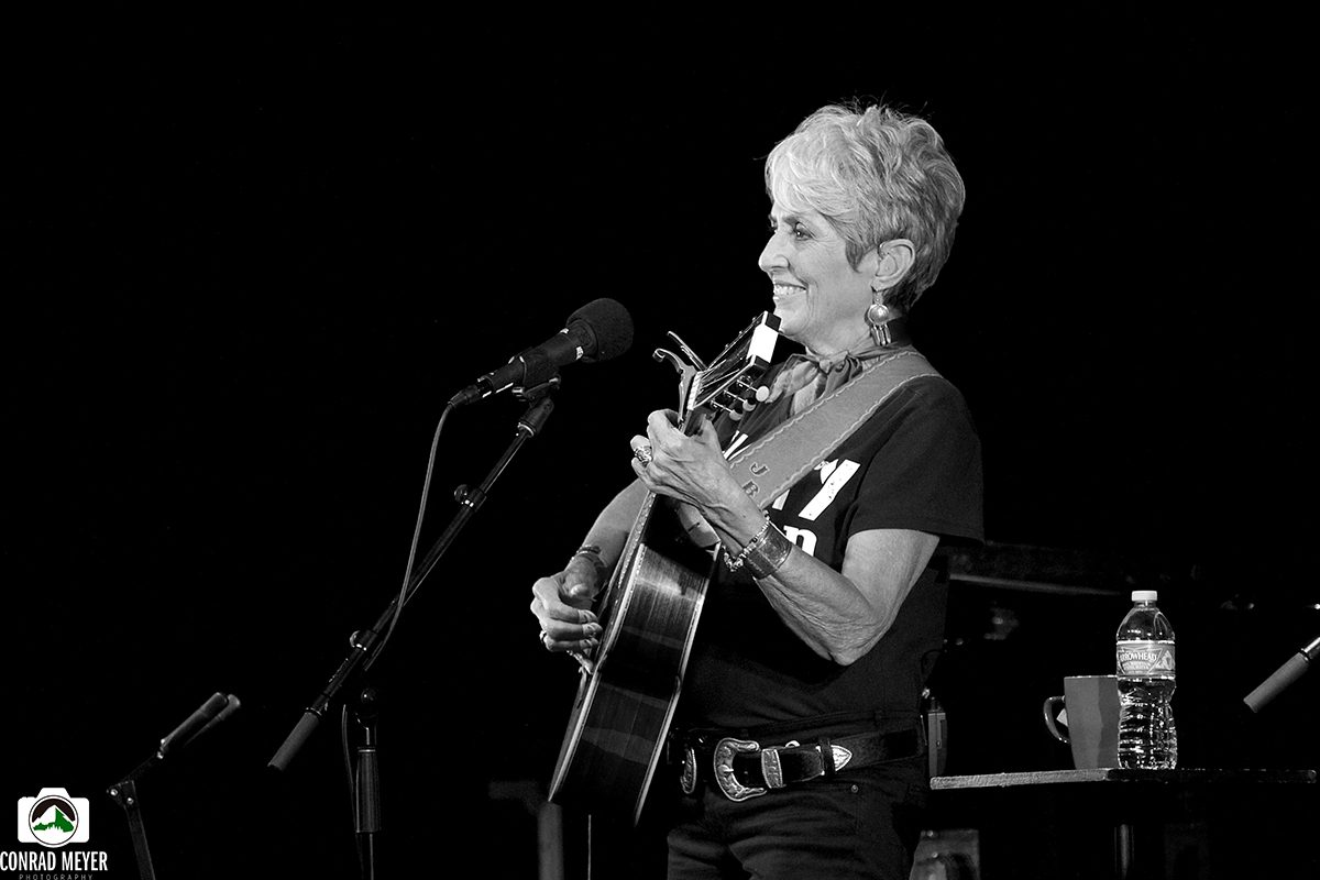 Musician performing with guitar on stage.
