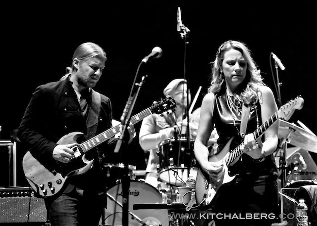 Musicians performing live with guitars on stage.