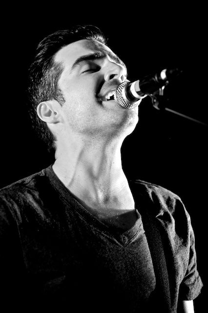Singer passionately performing on stage, black background.