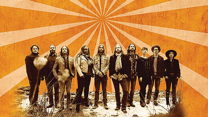 Band standing against an orange sunburst background.