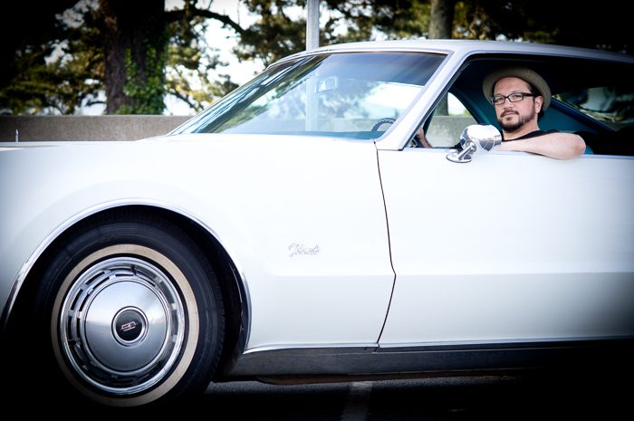 Man driving a vintage white car.