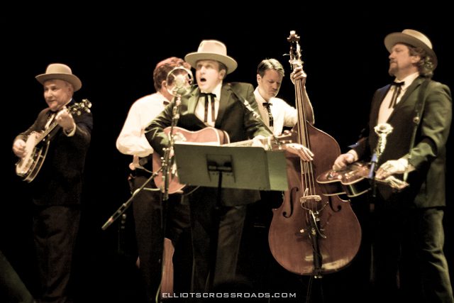 Band performing on stage with various instruments.