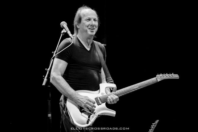 Musician playing electric guitar on stage.