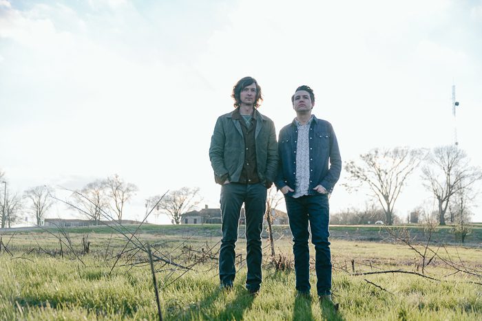Two men standing in a grassy field.
