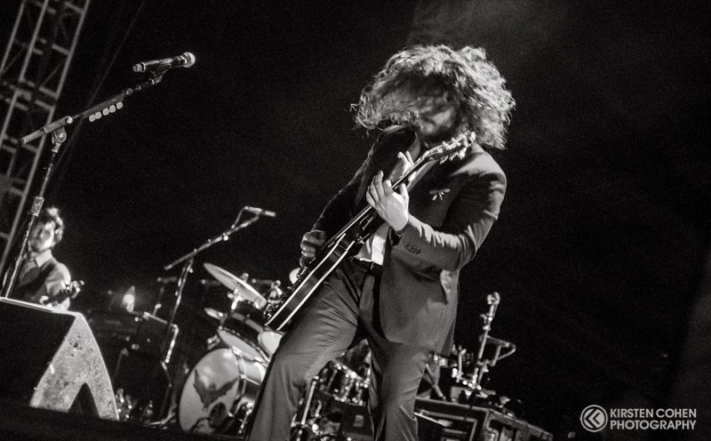 Guitarist performing energetically on stage.