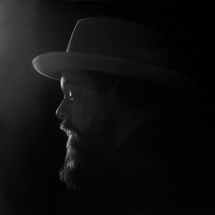 Silhouetted man in hat with beard.
