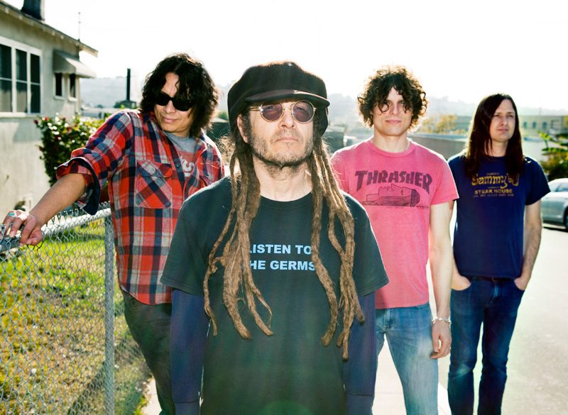 Band members posing outdoors in casual attire.