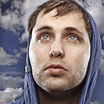 Man in hoodie looking up at sky.